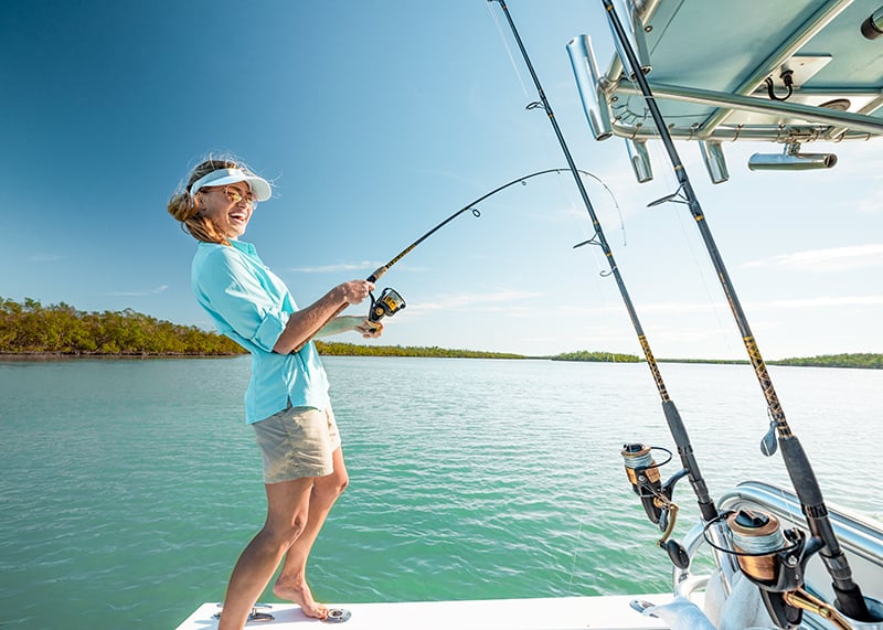 Woman Reeling In Fish From Boat Off Of Keewaydin Island